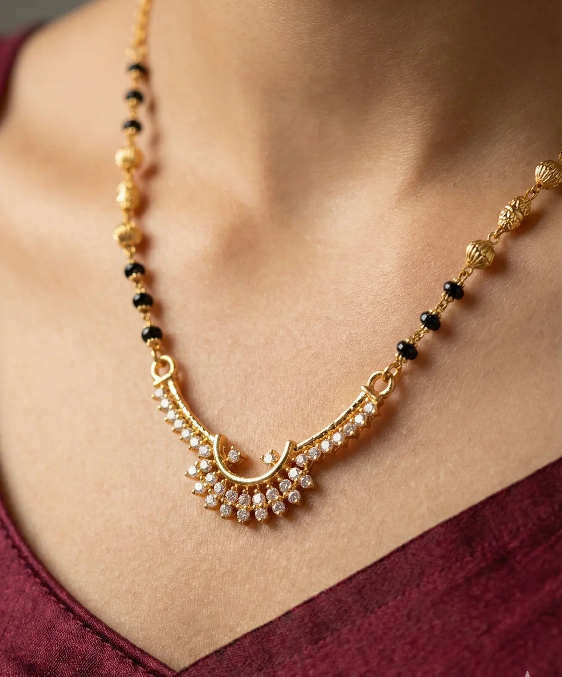 Gold necklace with black beads on a person wearing a maroon top