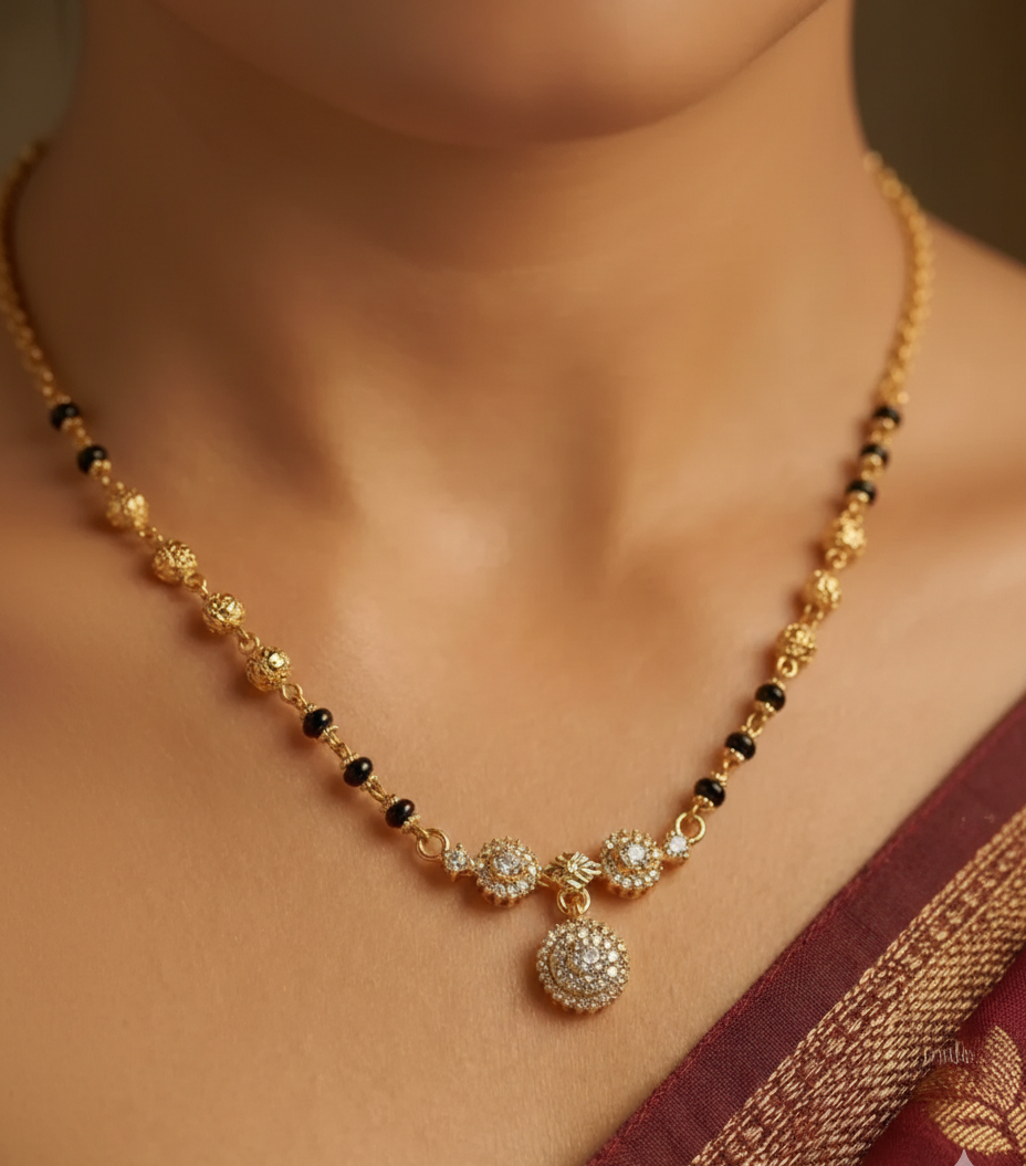 Gold necklace with black beads on a model wearing a saree