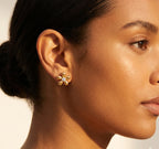 Close-up of a woman wearing a gold flower-shaped earring with a diamond center.