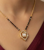 Gold necklace with black beads and a diamond pendant on a person wearing a burgundy top.