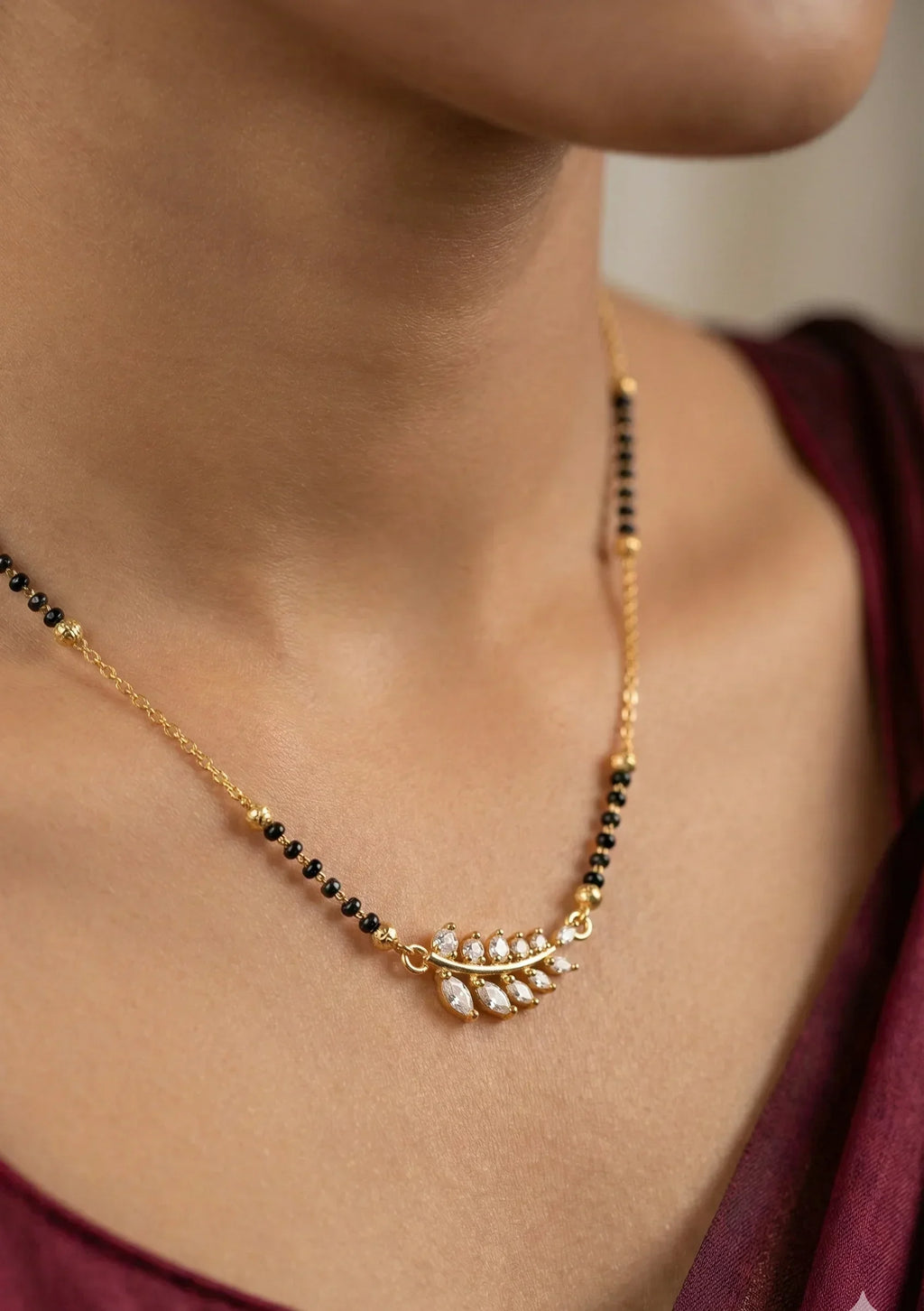Gold necklace with black beads worn by a person