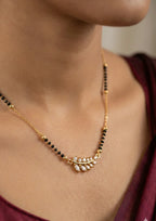 Gold necklace with black beads worn by a person