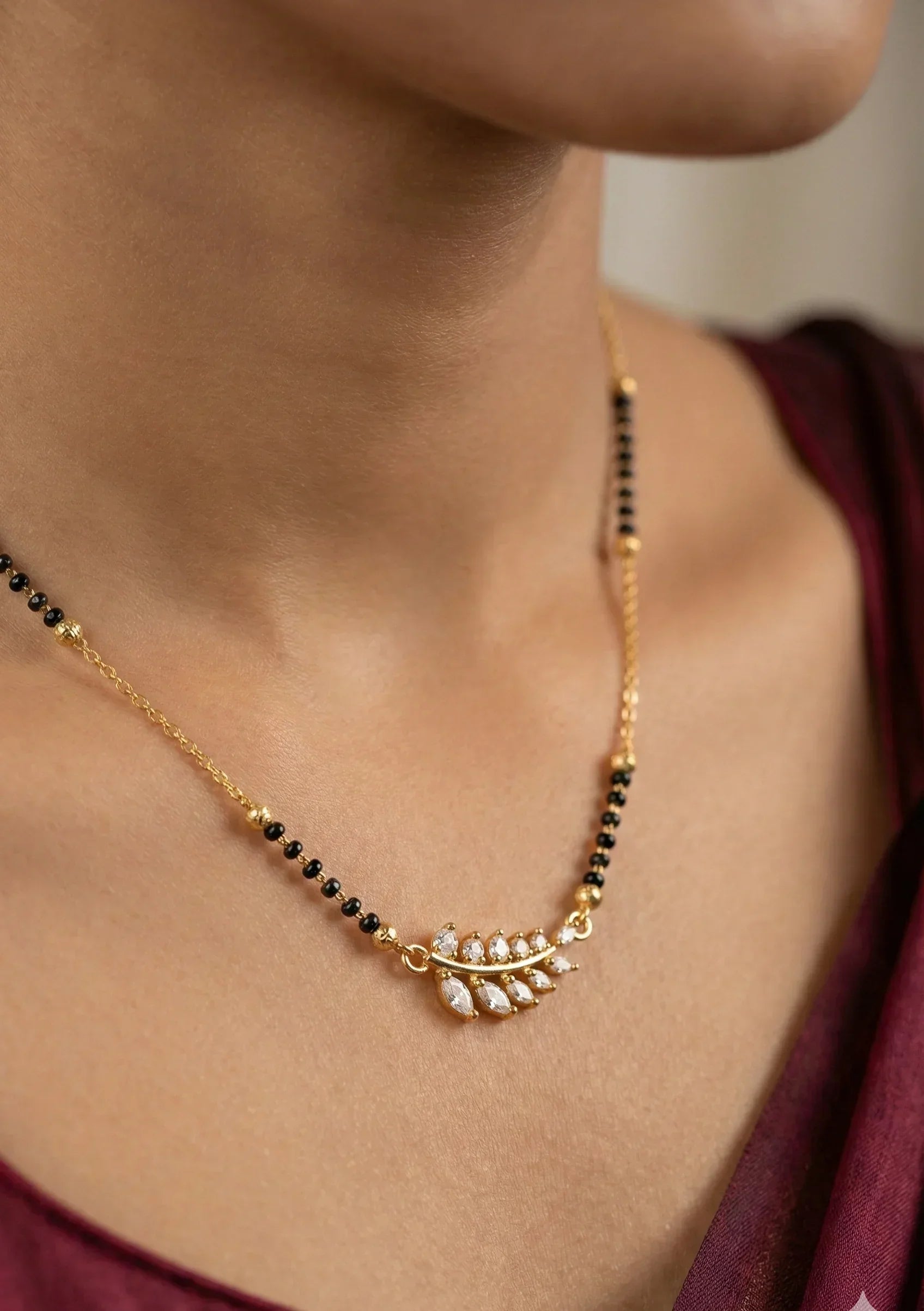 Gold necklace with black beads worn by a person