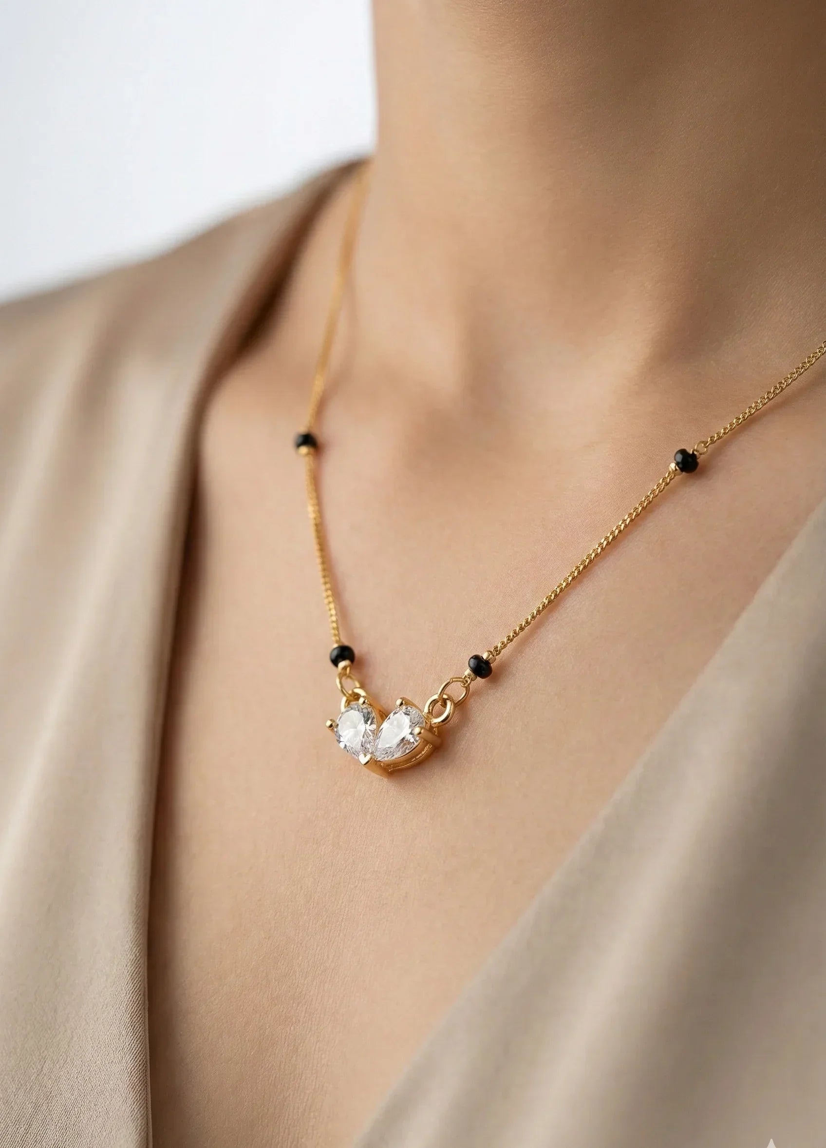 Gold necklace with a pendant on a person wearing a beige top.