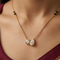 Gold necklace with two teardrop-shaped diamonds on a person wearing a burgundy top.