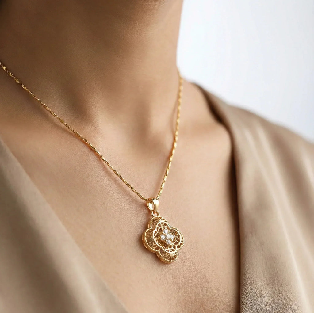 Gold necklace with a decorative pendant worn by a person against a neutral background