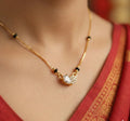 Gold necklace with a pendant on a person wearing a red garment.