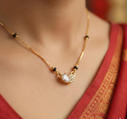 Gold necklace with a pendant on a person wearing a red garment.