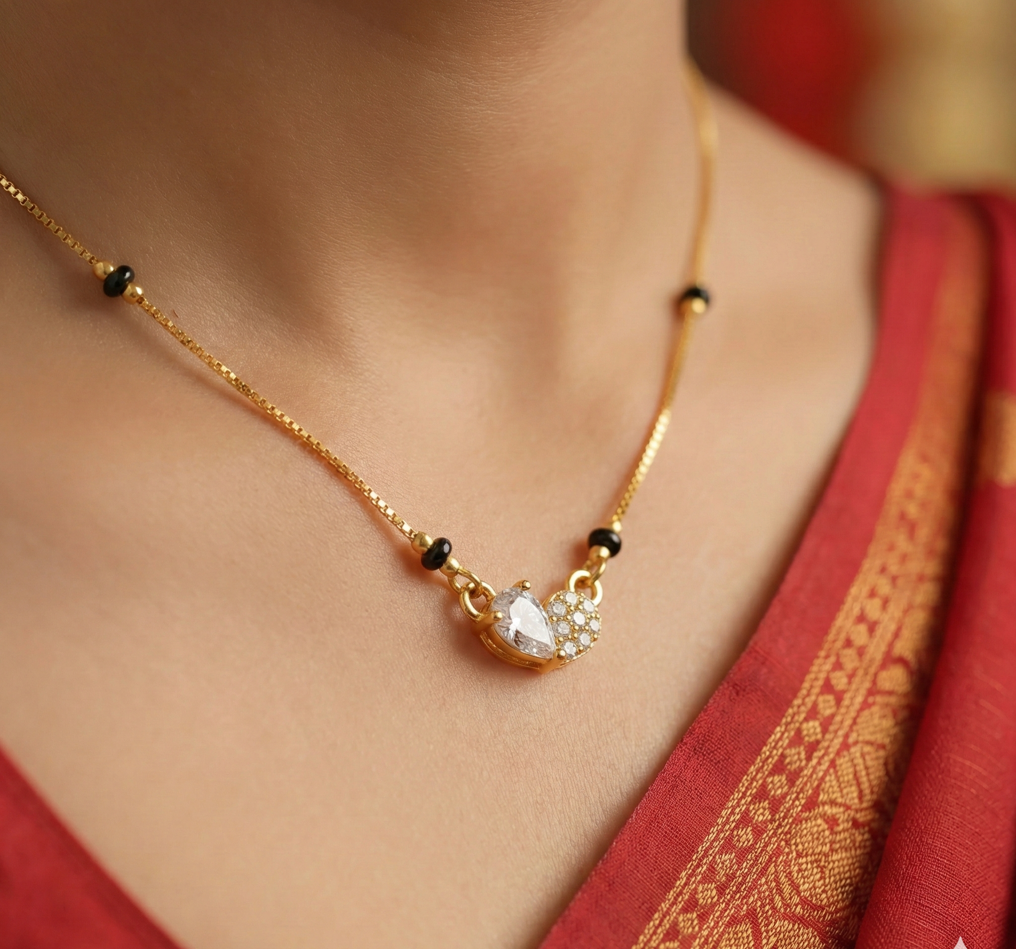 Gold necklace with a pendant on a person wearing a red garment.