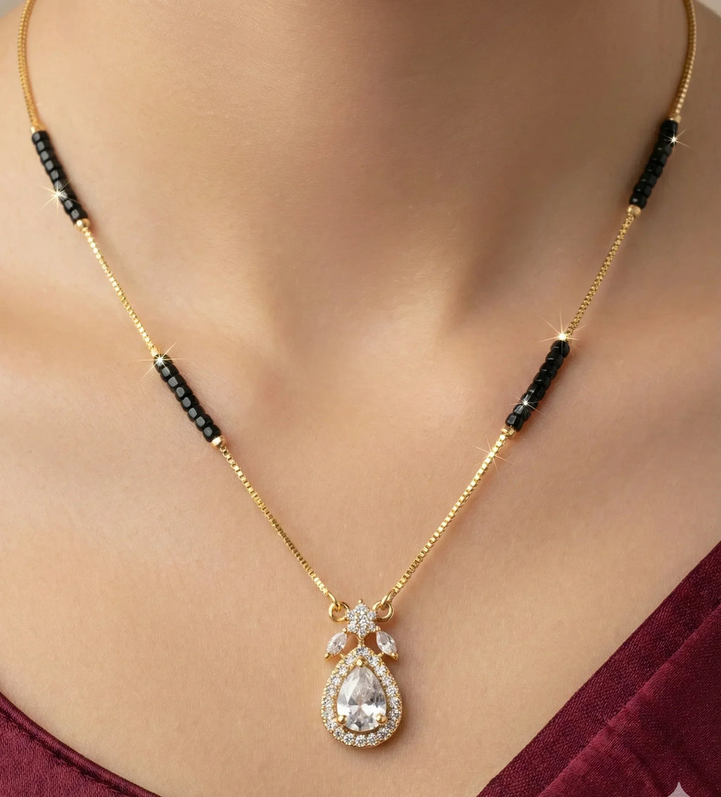 Gold necklace with a teardrop-shaped pendant worn by a person