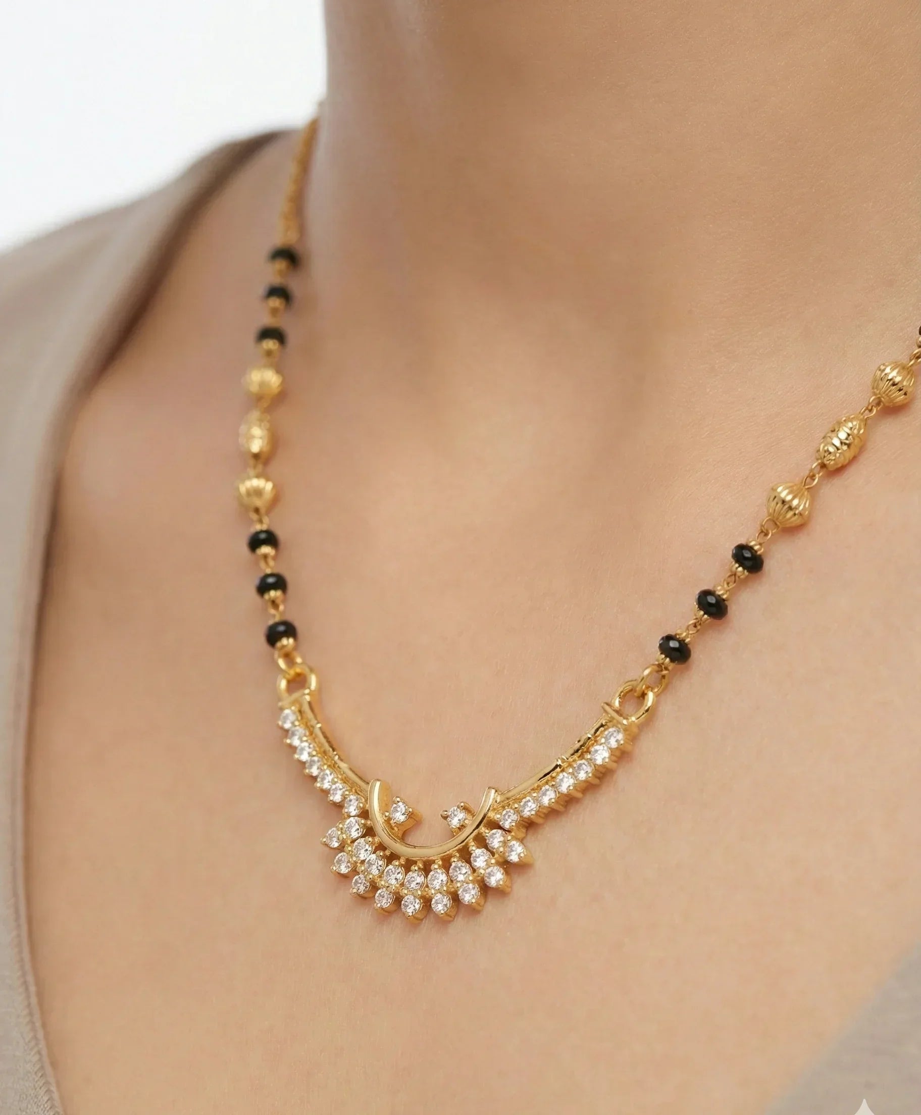 Gold necklace with black beads on a model against a neutral background