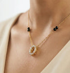 Gold necklace with a pendant on a person wearing a beige top.