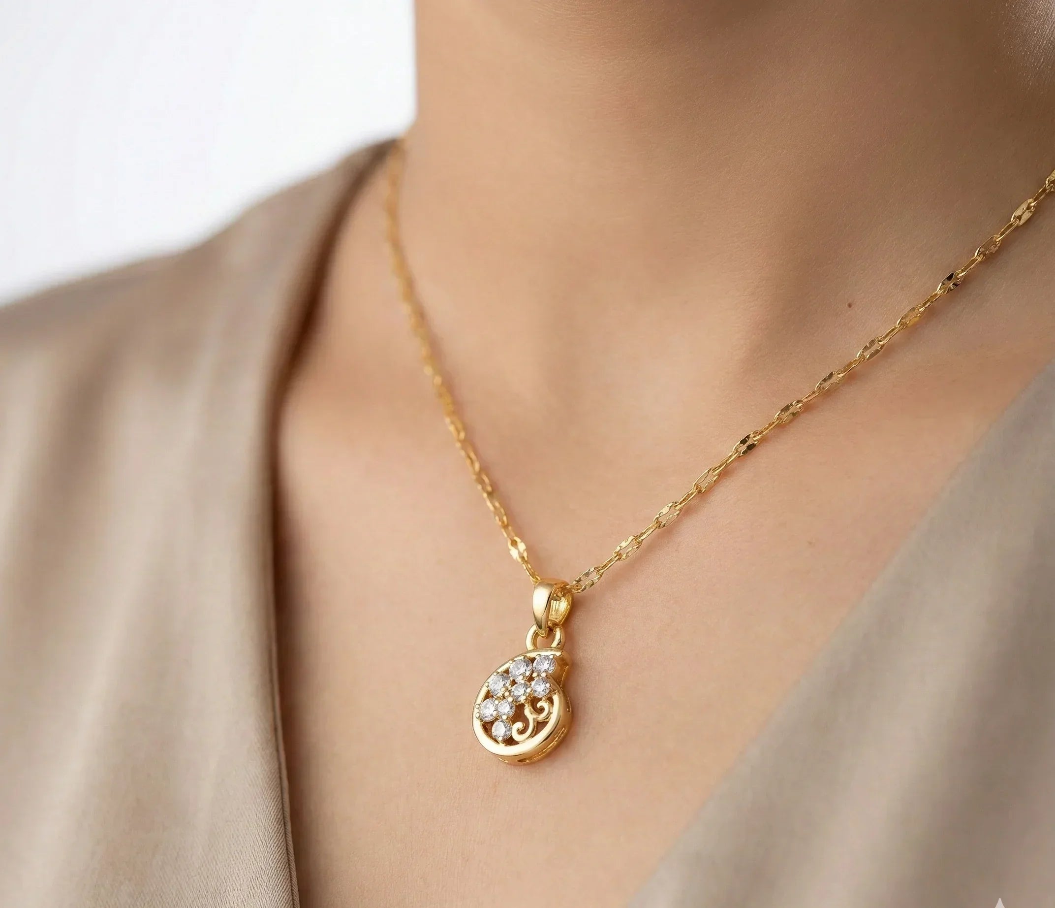 Gold necklace with a pendant on a person wearing a beige top