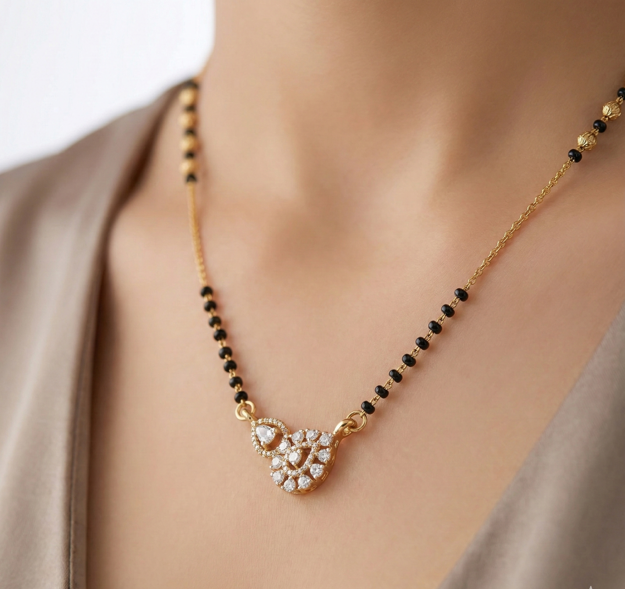 Gold necklace with black beads and a heart-shaped pendant on a neutral background