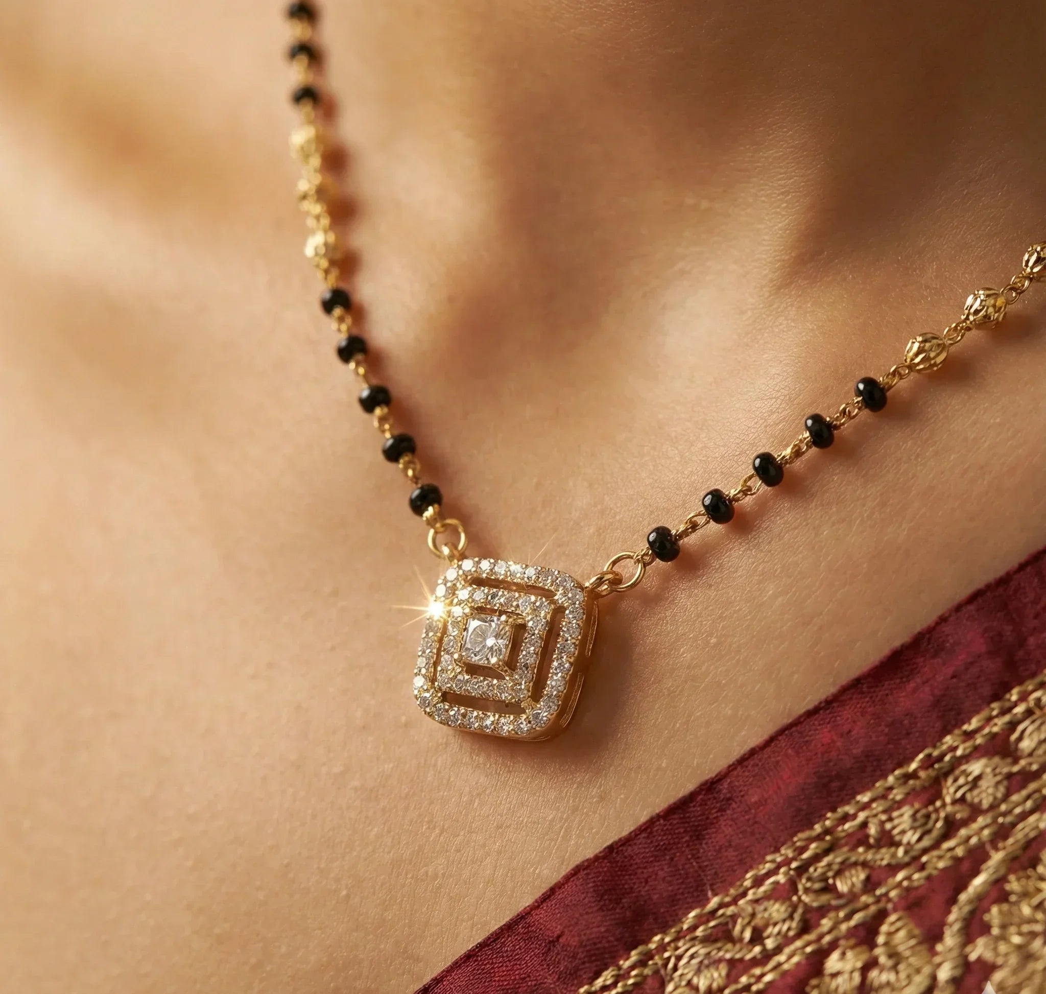 Gold necklace with a square pendant on a person wearing a red saree.