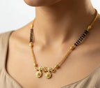Gold necklace with black beads on a neutral background