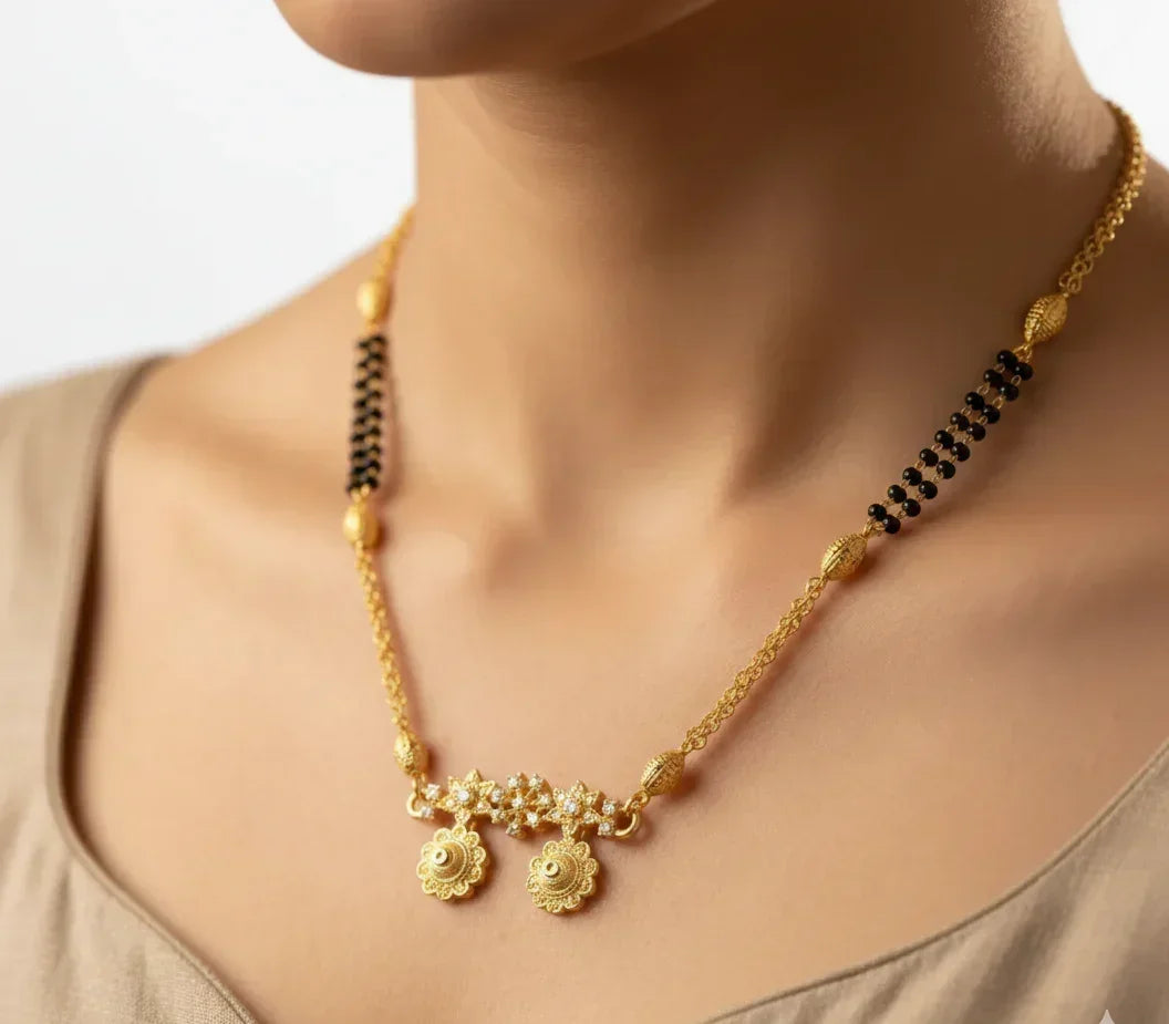 Gold necklace with black beads on a neutral background