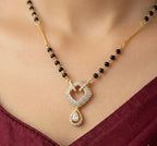 Necklace with a heart-shaped pendant and black beads on a person wearing a red garment.
