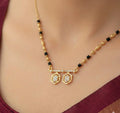Gold necklace with black beads and diamond-like pendants on a person wearing a maroon top.