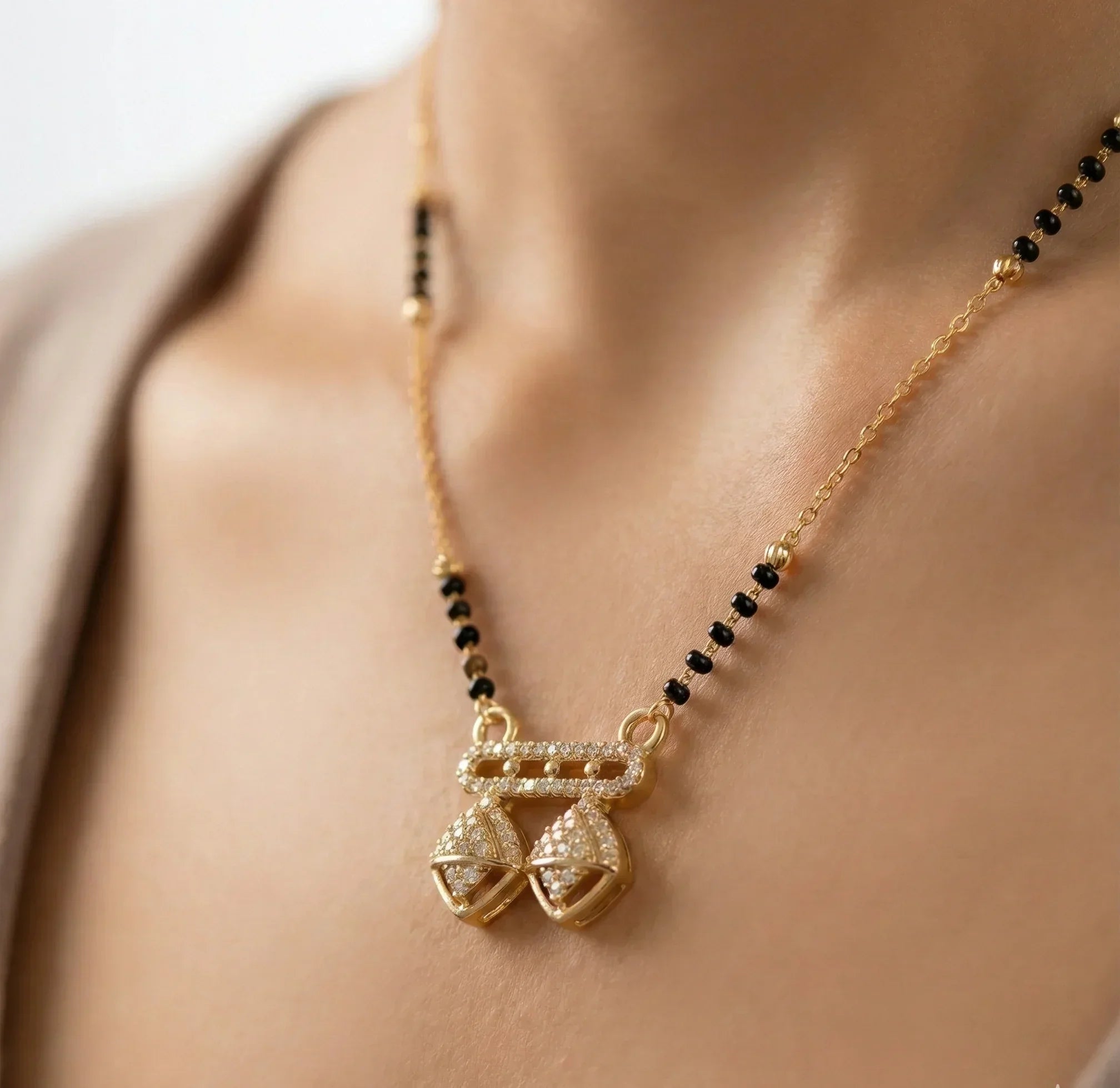 Gold necklace with black beads and a pendant on a person's neck
