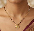 Gold necklace with a pendant on a person wearing a saree
