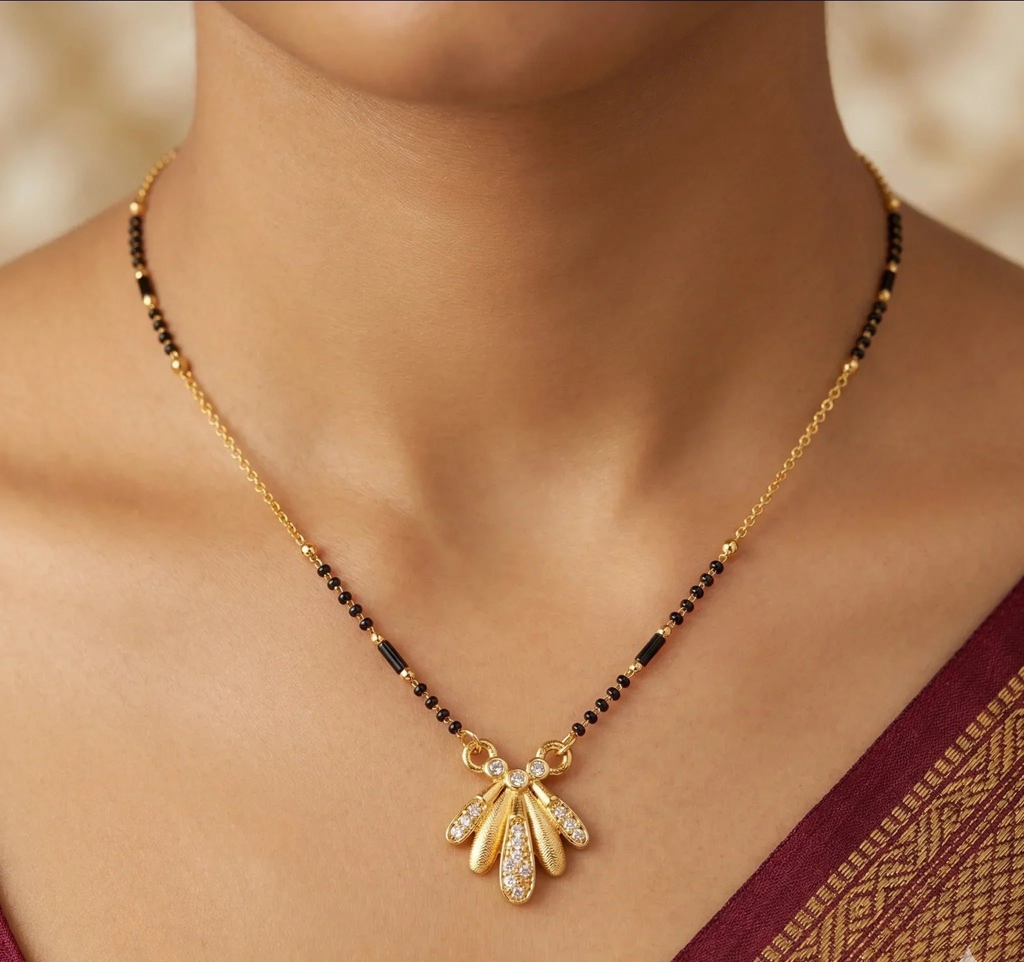 Gold necklace with a pendant on a person wearing a saree