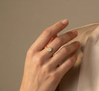 Hand wearing a rose gold ring with a diamond on a beige background