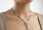 Gold necklace with a key-shaped pendant on a neutral background