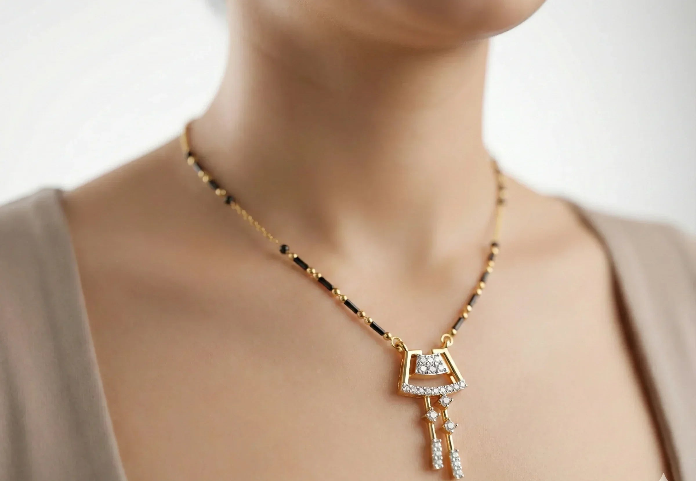 Gold necklace with a key-shaped pendant on a neutral background