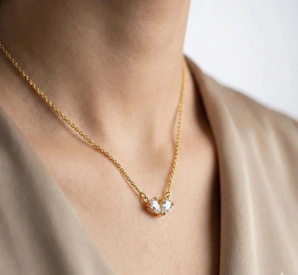 Gold necklace with a heart-shaped pendant on a neutral background
