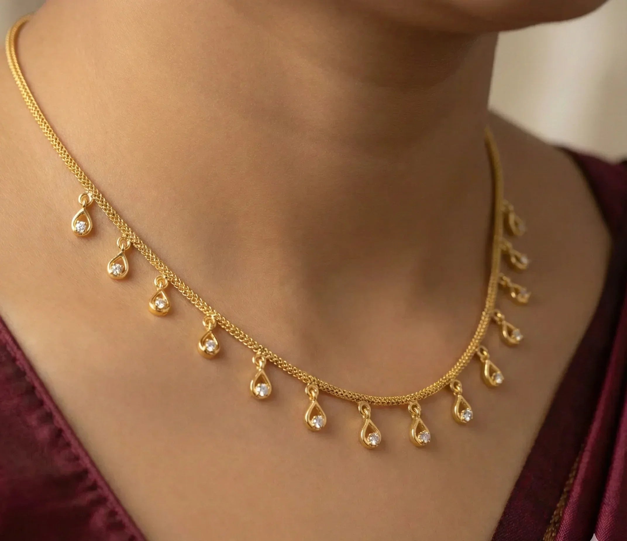 Gold necklace with teardrop-shaped pendants worn by a person