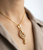 Gold necklace with a detailed pendant worn by a person