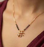 Gold necklace with a hashtag pendant on a person wearing a burgundy top.