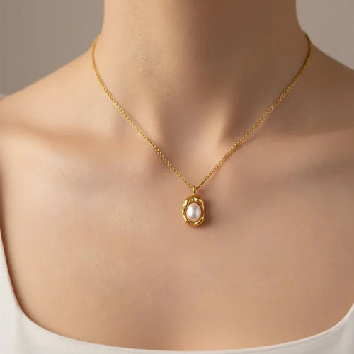 Gold necklace with a pearl pendant on a neutral background