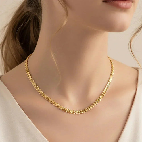 Gold necklace worn by a model against a neutral background