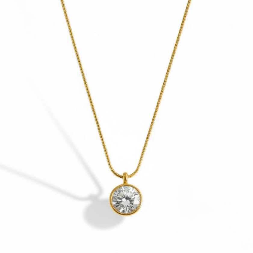 Gold necklace with a clear gemstone pendant on a white background