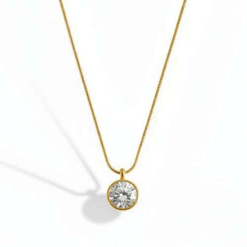 Gold necklace with a clear gemstone pendant on a white background