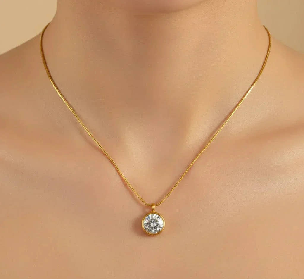 Gold necklace with a diamond pendant on a neutral background