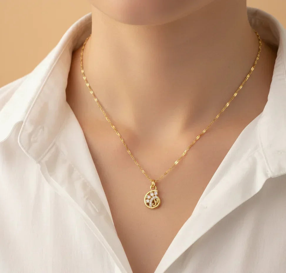 Gold necklace with a pendant on a mannequin wearing a white shirt against a beige background