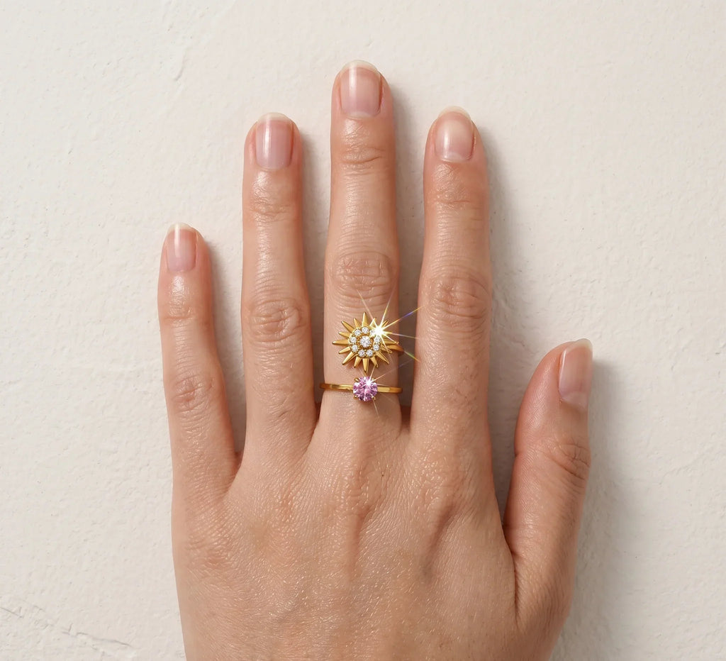 Hand wearing a gold ring with a star-shaped design on a light background