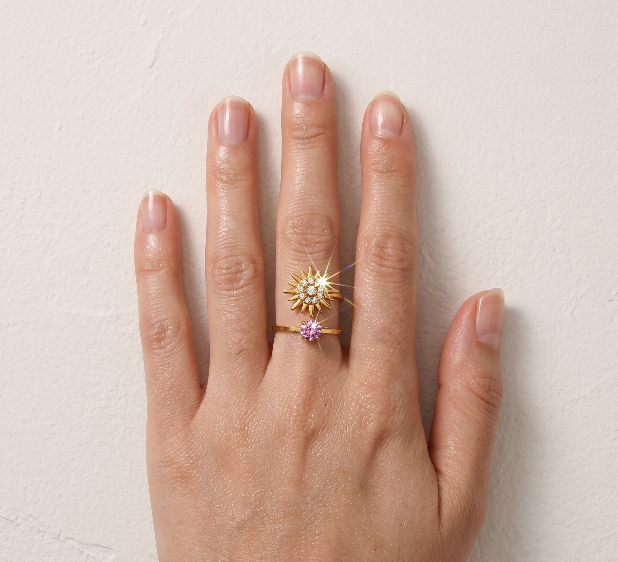 Hand wearing a gold ring with a star-shaped design on a light background